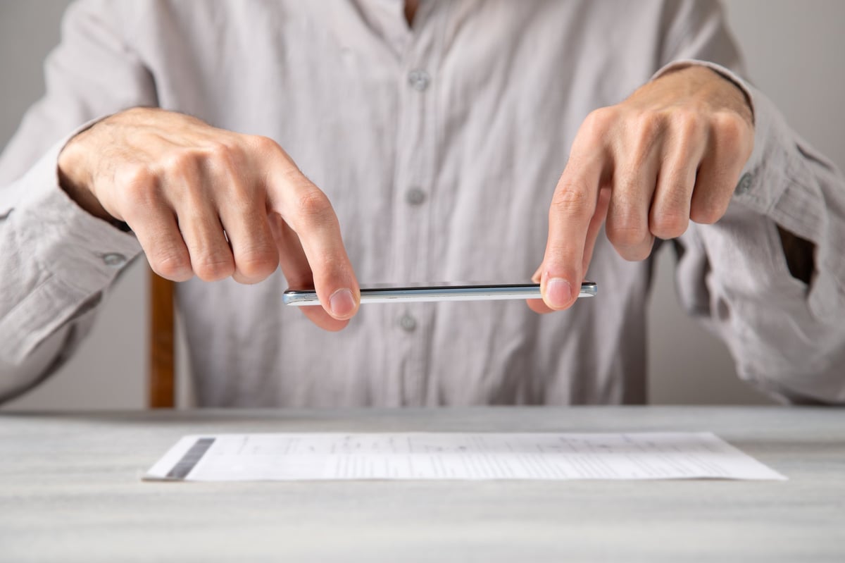 Business person taking a photo of a vehicle document with a smartphone, recording evidence for the record